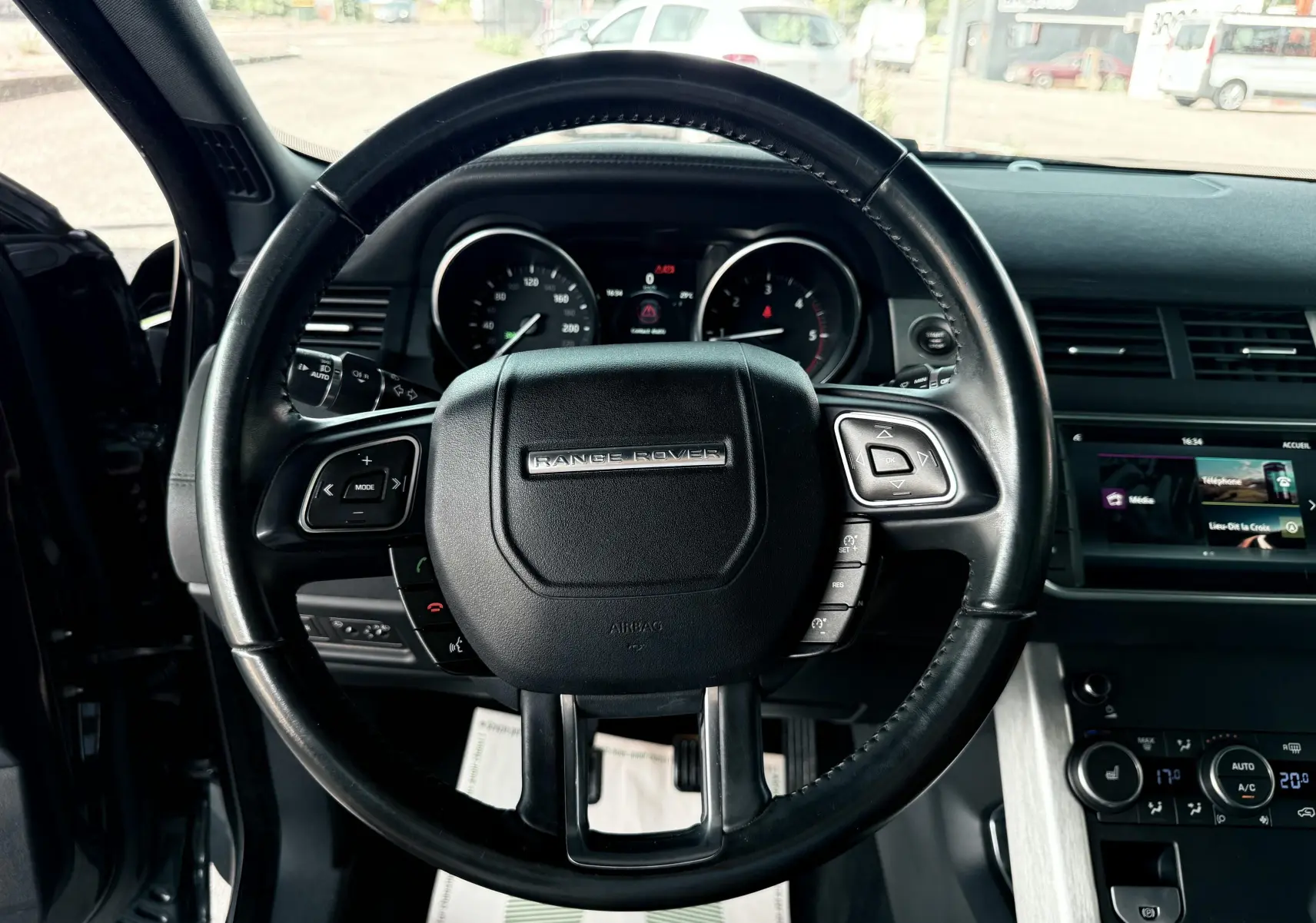 Volant noir de Range Rover Evoque 2017 vu de face avec tableau de bord et écran tactile en arrière-plan