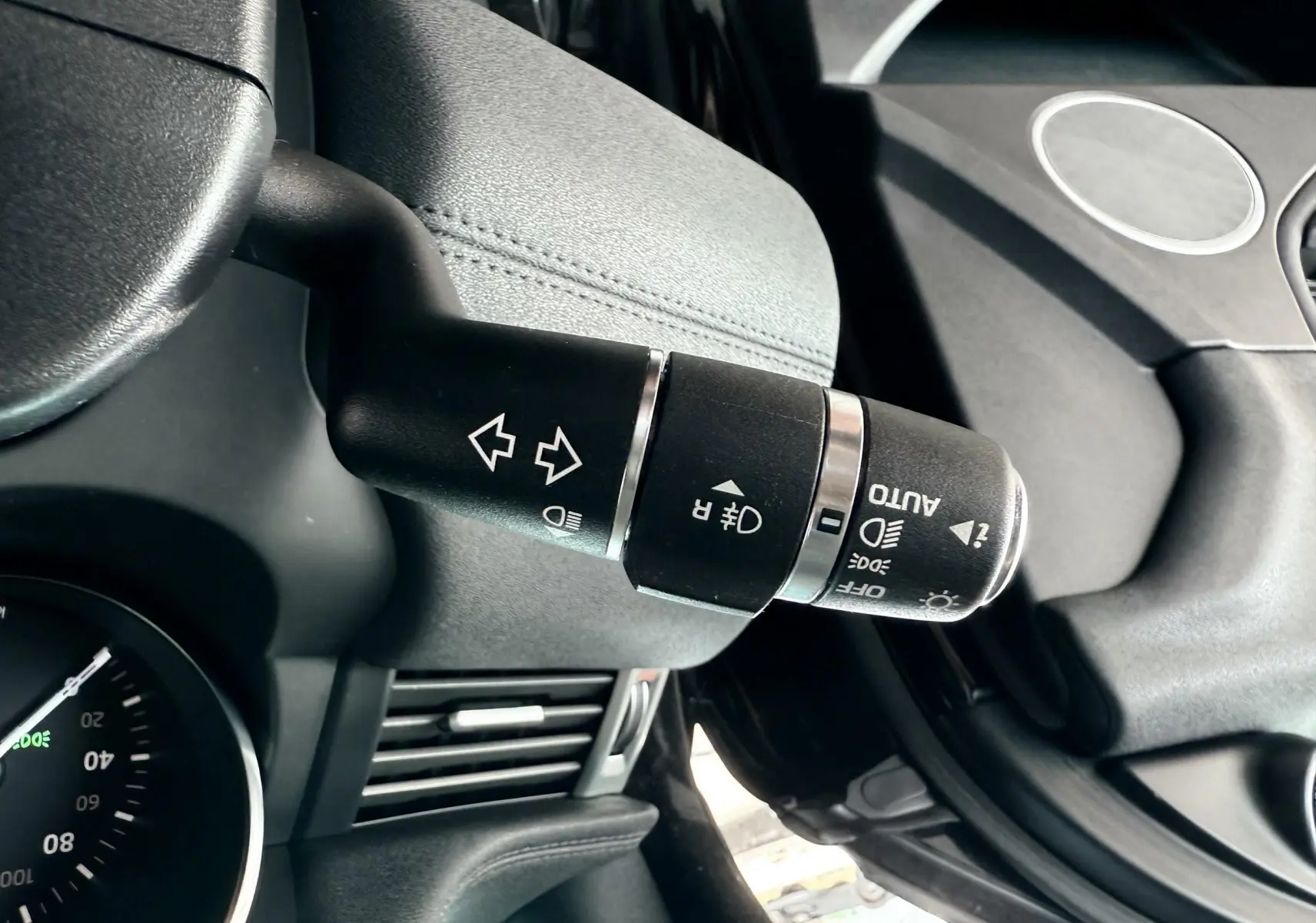 Gros plan sur la commande des feux et clignotants noire dans l'habitacle du Range Rover Evoque noir de 2017.