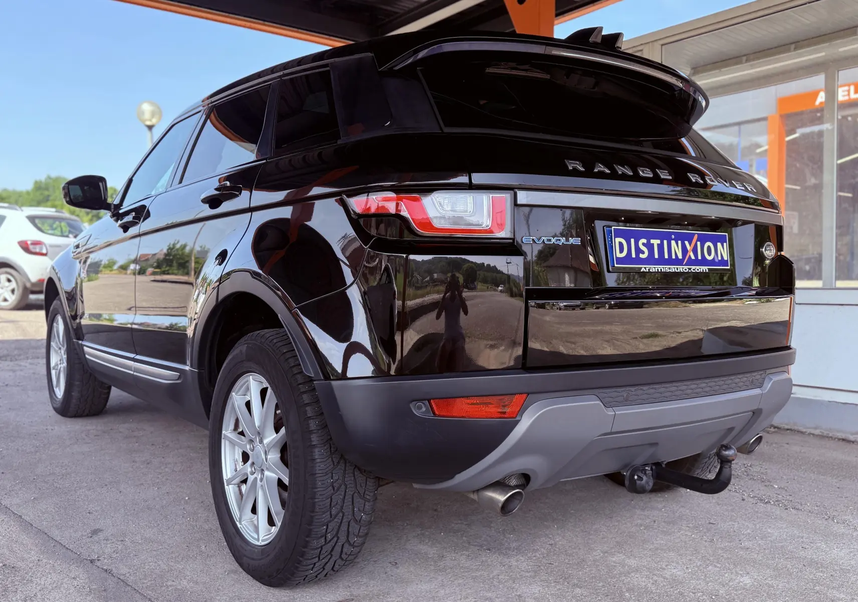 Vue 3/4 arrière gauche d'un Range Rover Evoque noir avec attelage et jantes argentées sous un abri.