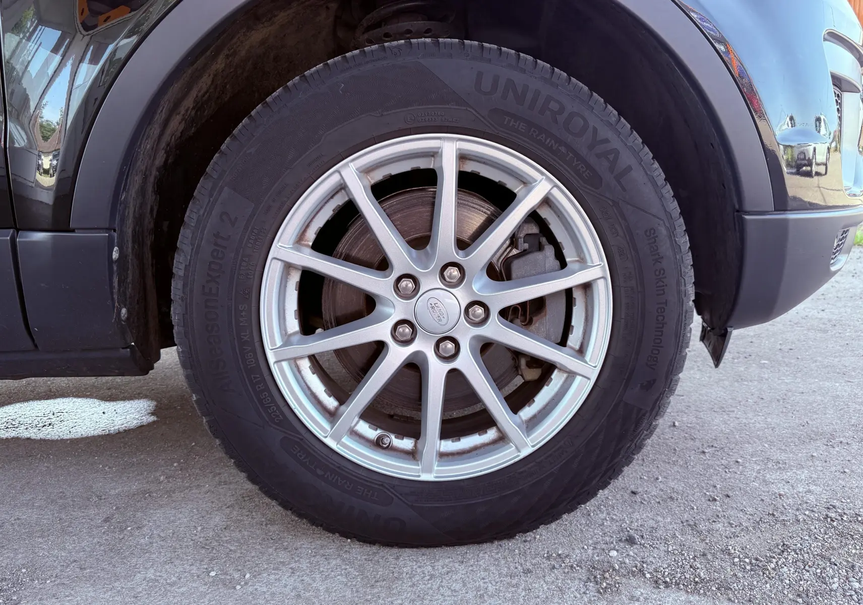 Gros plan sur la roue avant droite du Range Rover Evoque noir, mettant en valeur la jante argentée et le pneu Uniroyal.