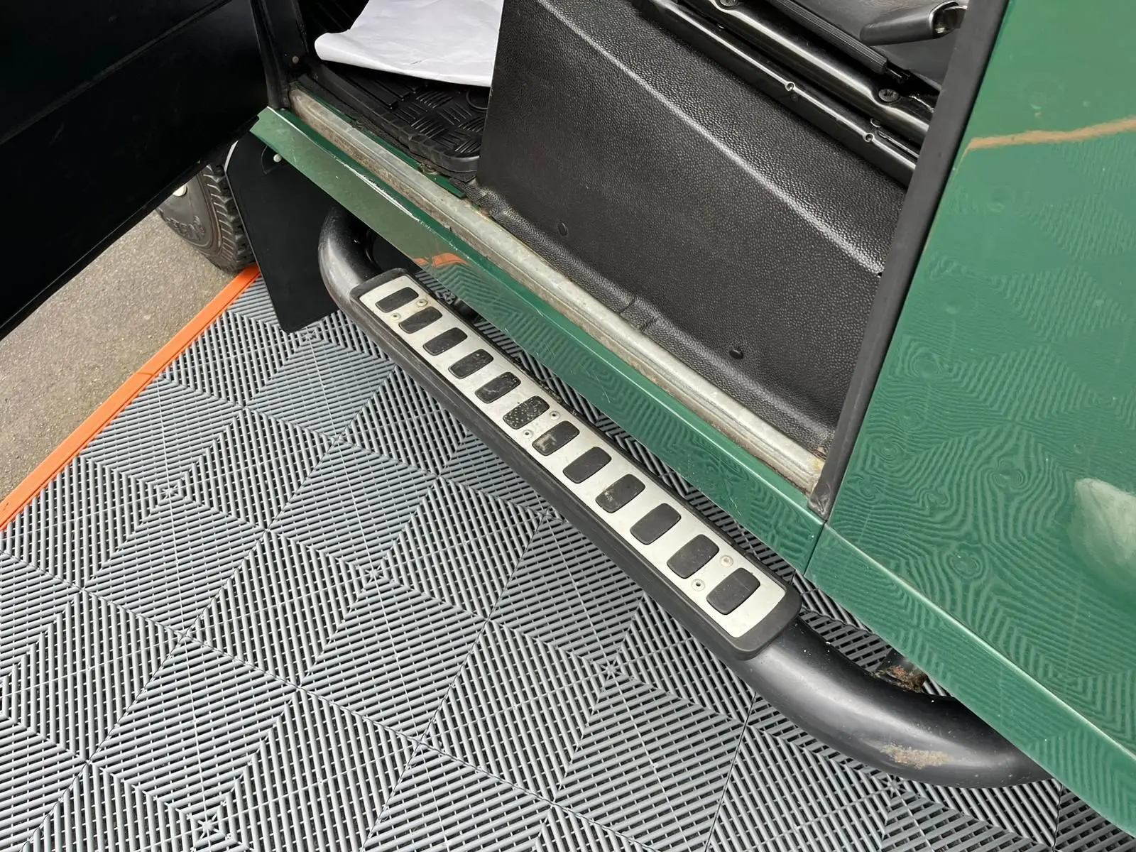 Gros plan sur le marchepied latéral droit vert d’un Land Rover Defender 90 Hard Top 2004 avec porte ouverte.