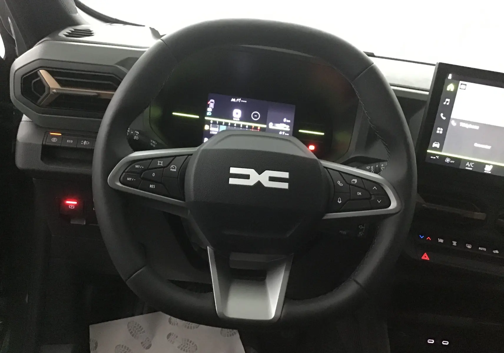 Vue frontale du volant du Dacia Duster 2025 avec tableau de bord numérique et écran tactile, intérieur moderne noir.