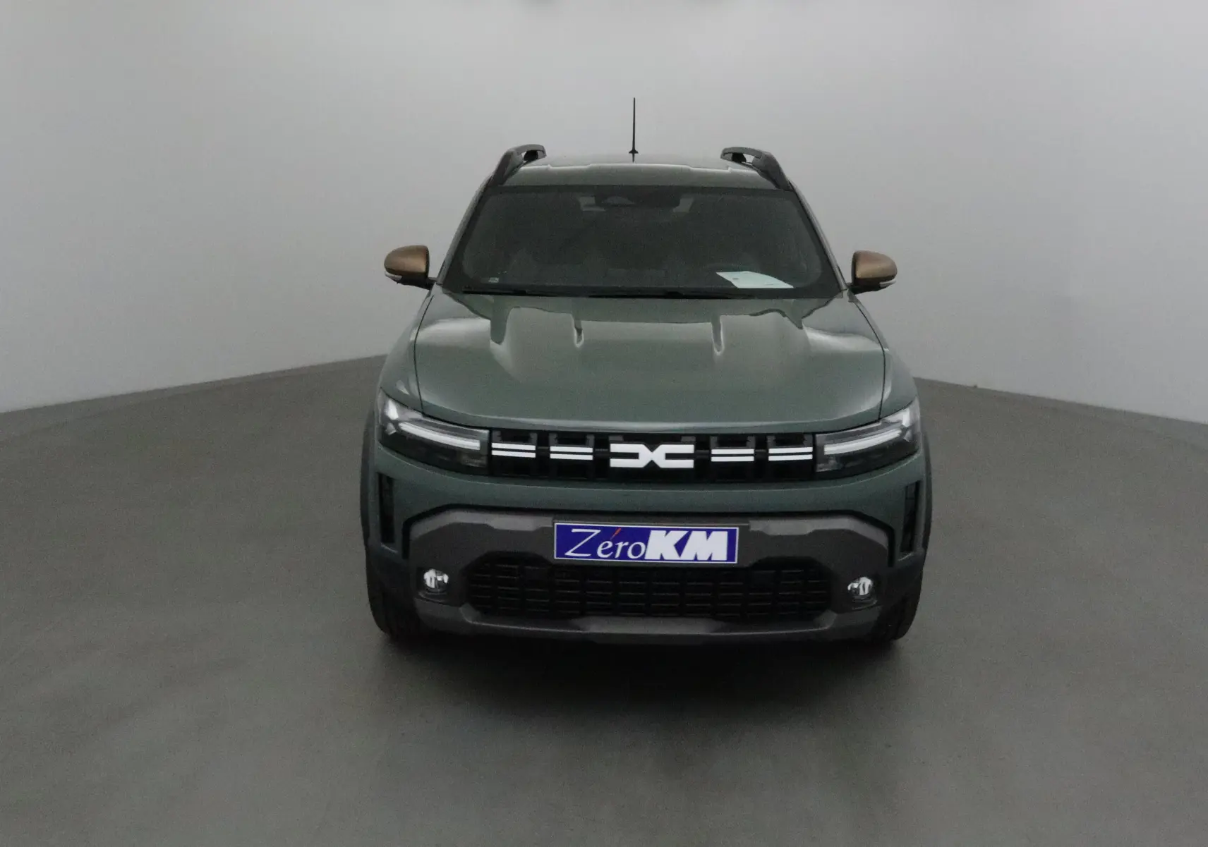 Vue frontale du Dacia Duster 2025 kaki lichen avec calandre distinctive et phares LED fins allumés.