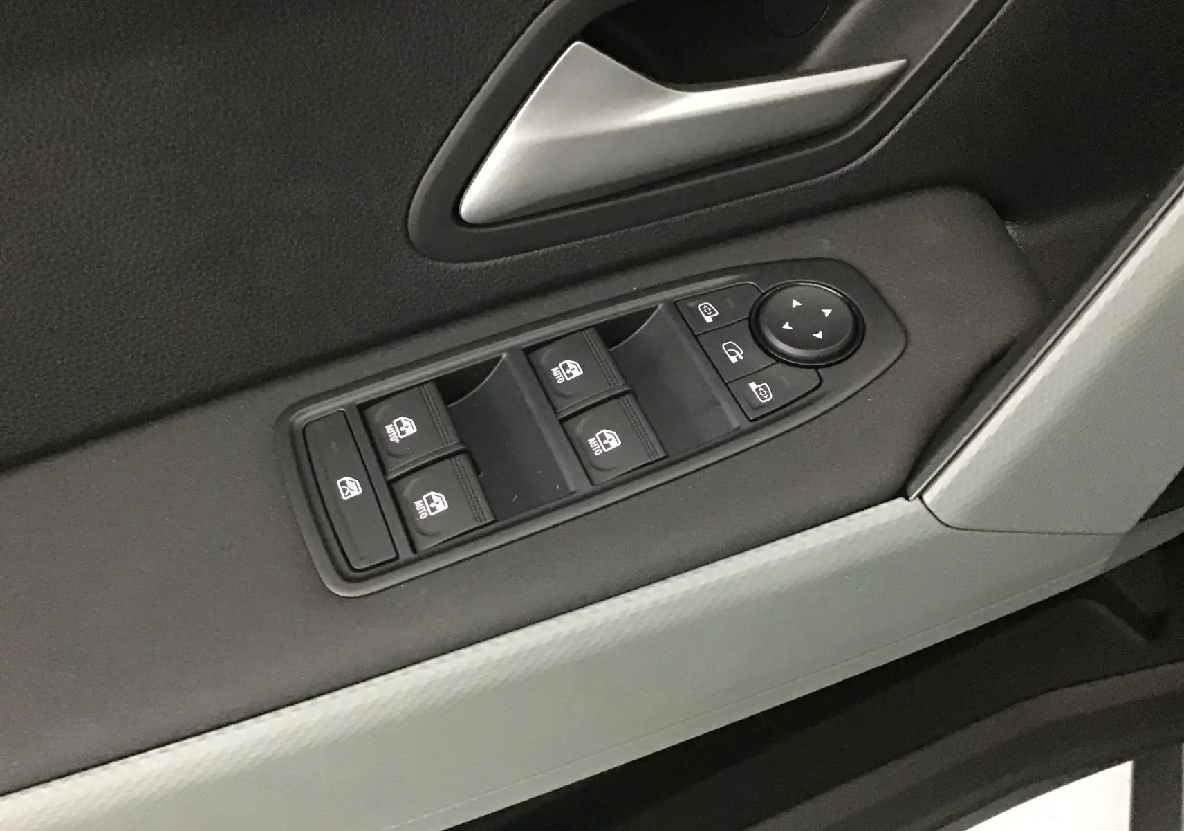 Gros plan sur les commandes des vitres électriques et rétroviseurs sur la porte côté gauche du Dacia Duster 2025.