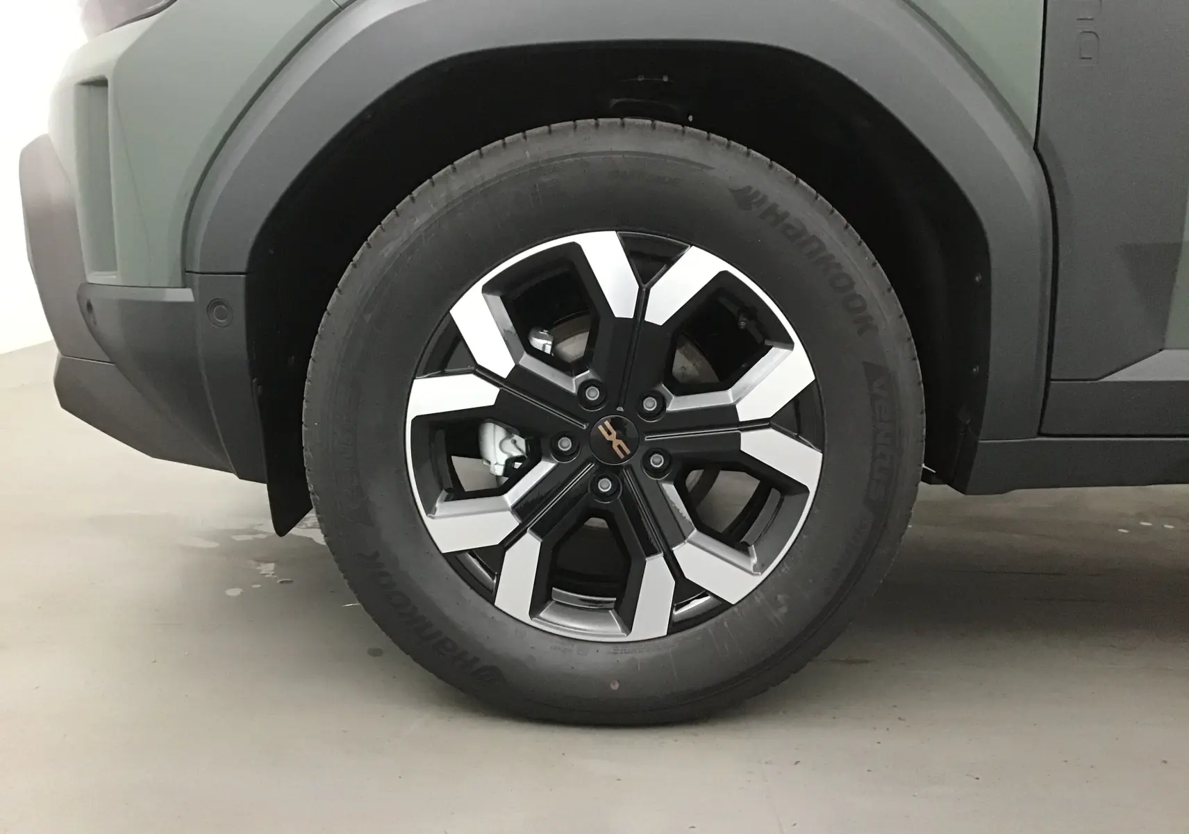 Gros plan sur la roue avant gauche du Dacia Duster kaki lichen 2025, mettant en valeur la jante alliage noire et argent.