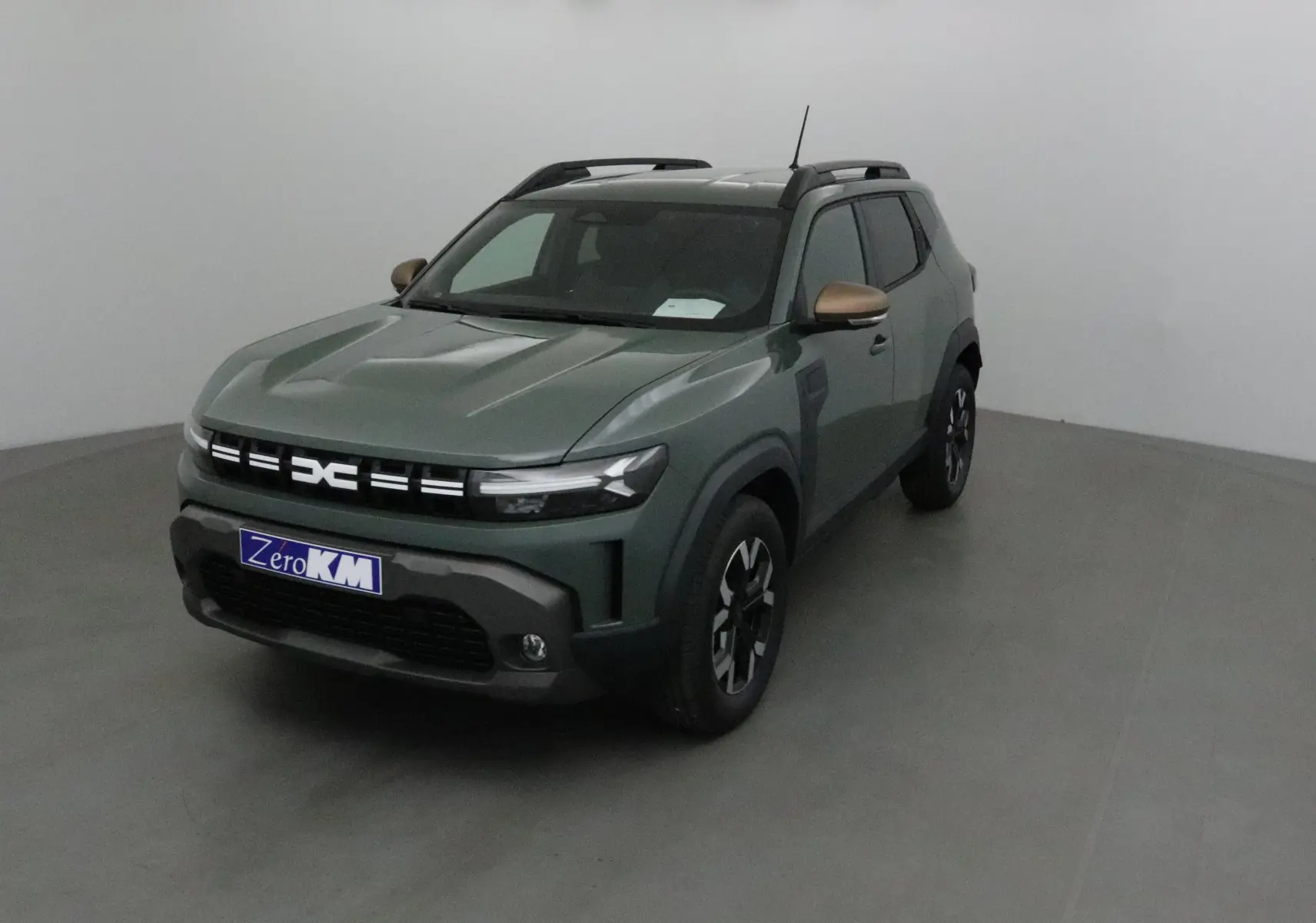 Dacia Duster kaki lichen en 3/4 avant droit avec rétroviseurs bronze et jantes noires bicolores.