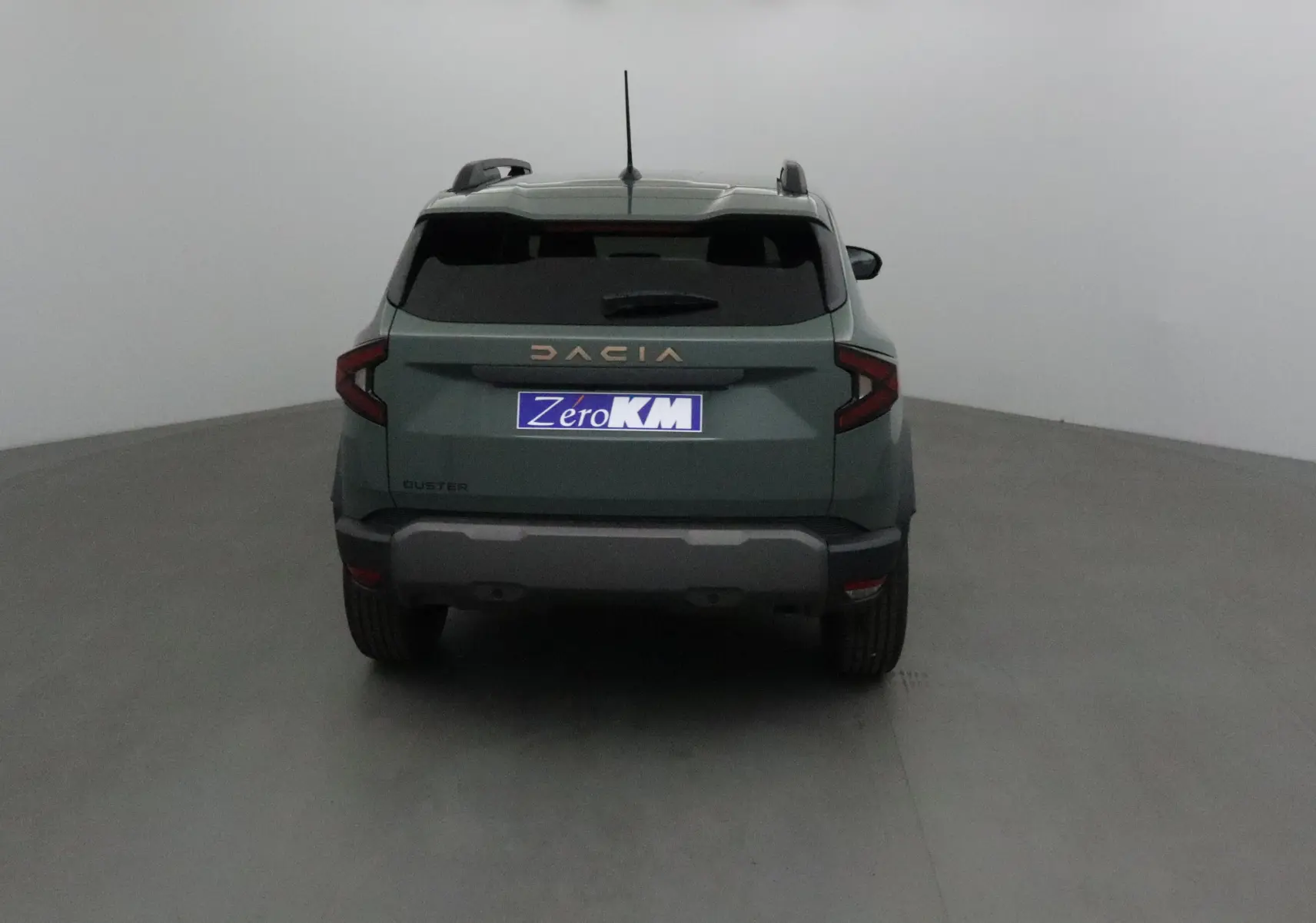 Vue arrière d'un Dacia Duster 2025 kaki lichen avec logo Dacia doré et plaque Zero KM visible.