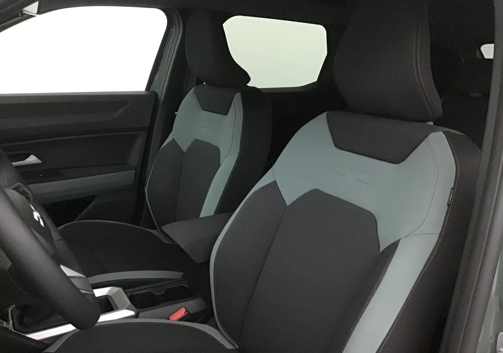 Vue intérieure rapprochée des sièges avant noirs et gris du Dacia Duster 2025 avec surpiqûres contrastées.