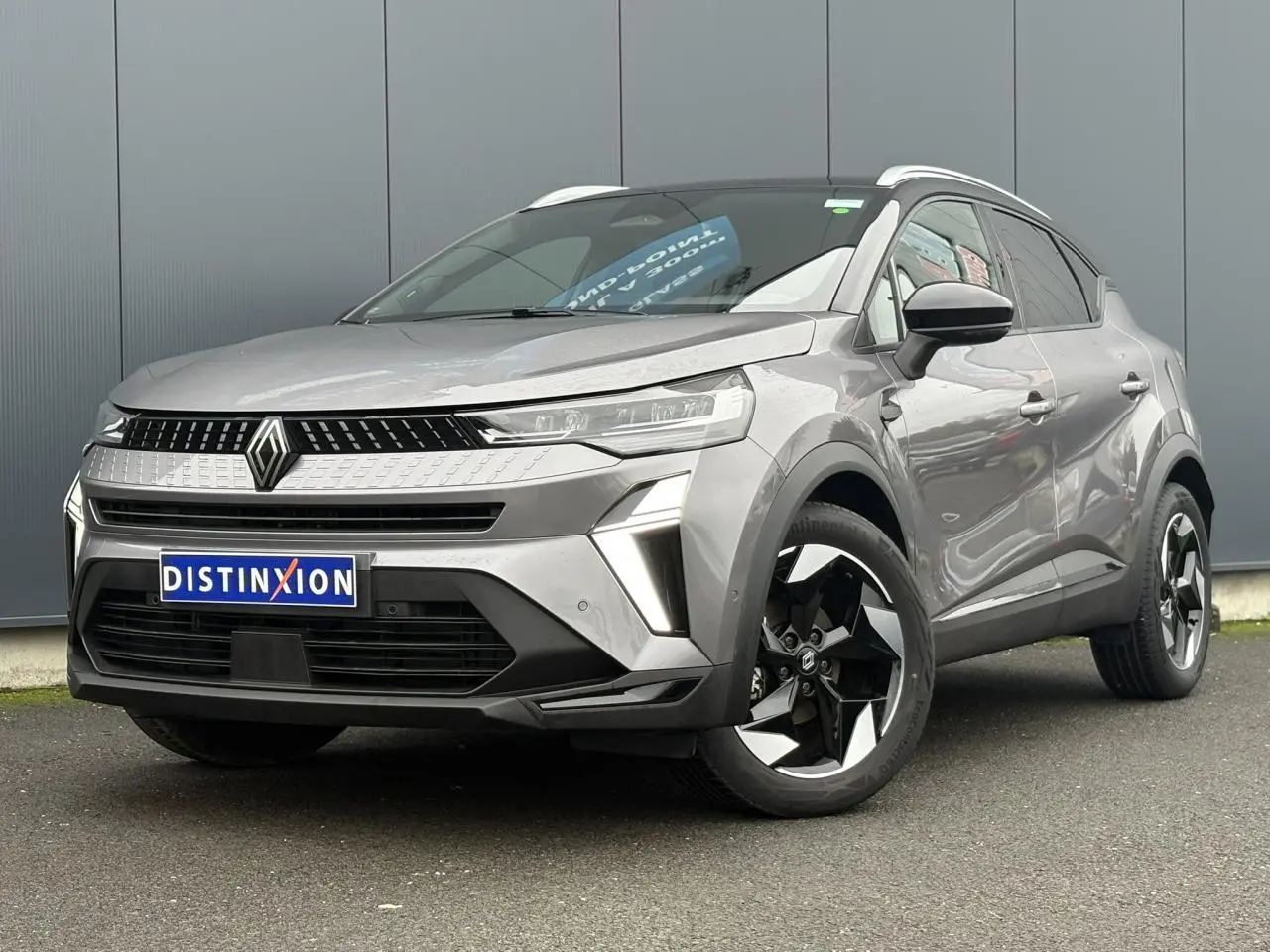 Renault Captur 2025 gris Cassiopée et noir, vue 3/4 avant droit, avec jantes alu diamantées noires et railing de toit alu.