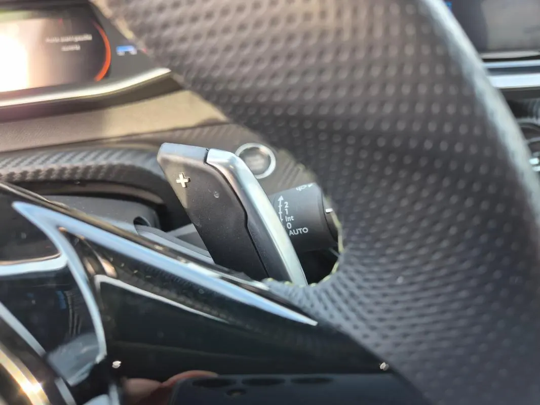 Gros plan sur la palette de changement de vitesse au volant du Peugeot 2008 Hybrid 145 e-DCS6 GT noir, intérieur moderne.