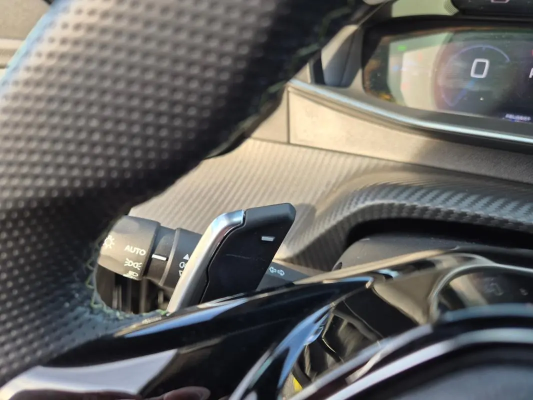 Gros plan sur la palette de changement de vitesse derrière le volant d’une Peugeot 2008 noir, intérieur carbone.