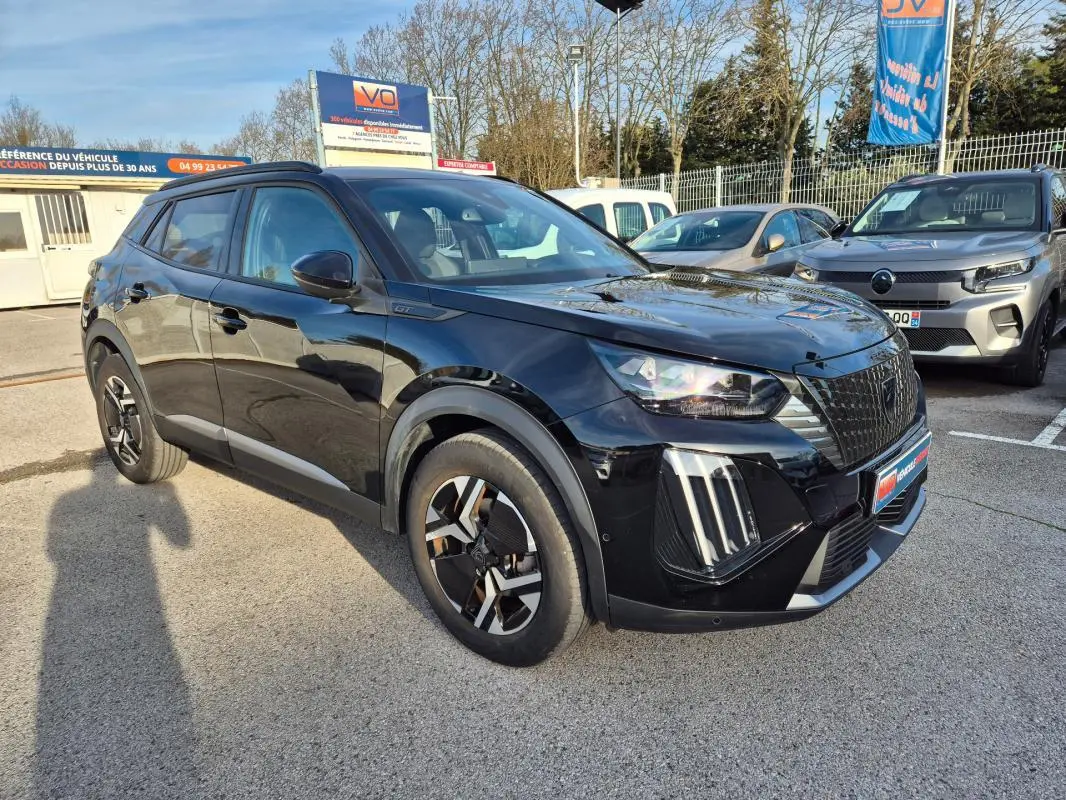 Peugeot 2008 Hybrid 145 e-DCS6 GT noir en 3/4 avant droit avec barres de toit et jantes alliage 18 pouces.