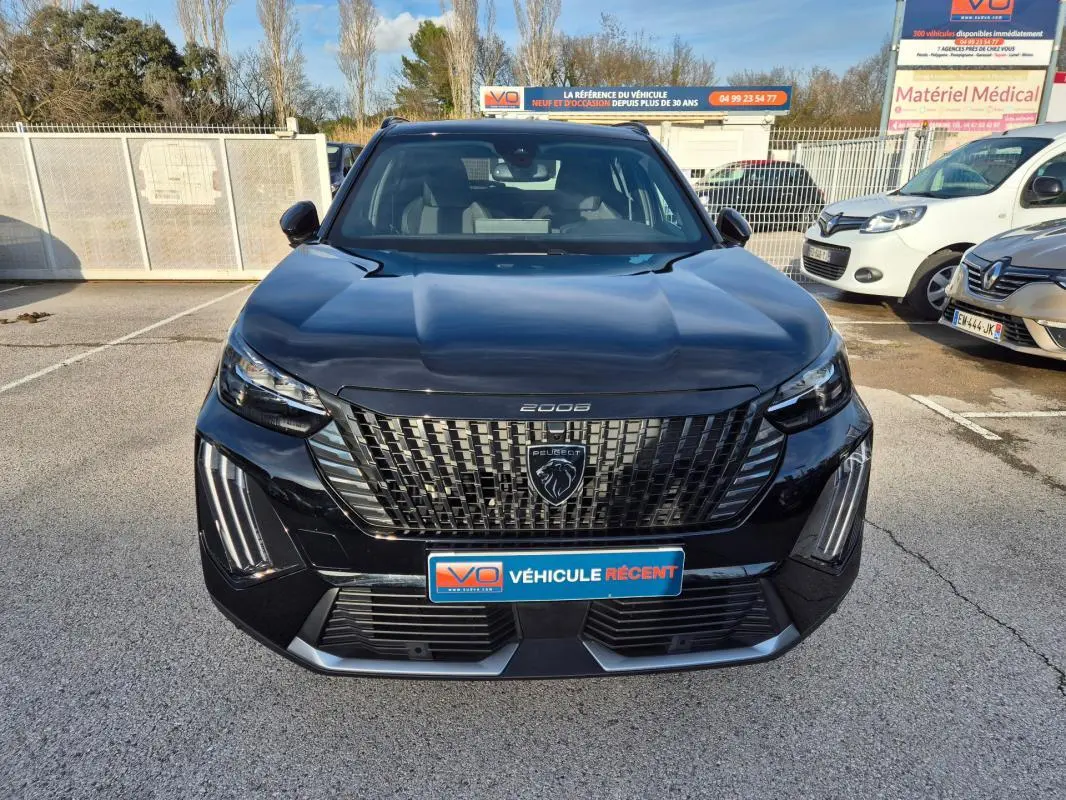 Vue frontale d’un Peugeot 2008 Hybrid 145 e-DCS6 GT noir avec calandre distinctive et feux LED verticaux allumés.
