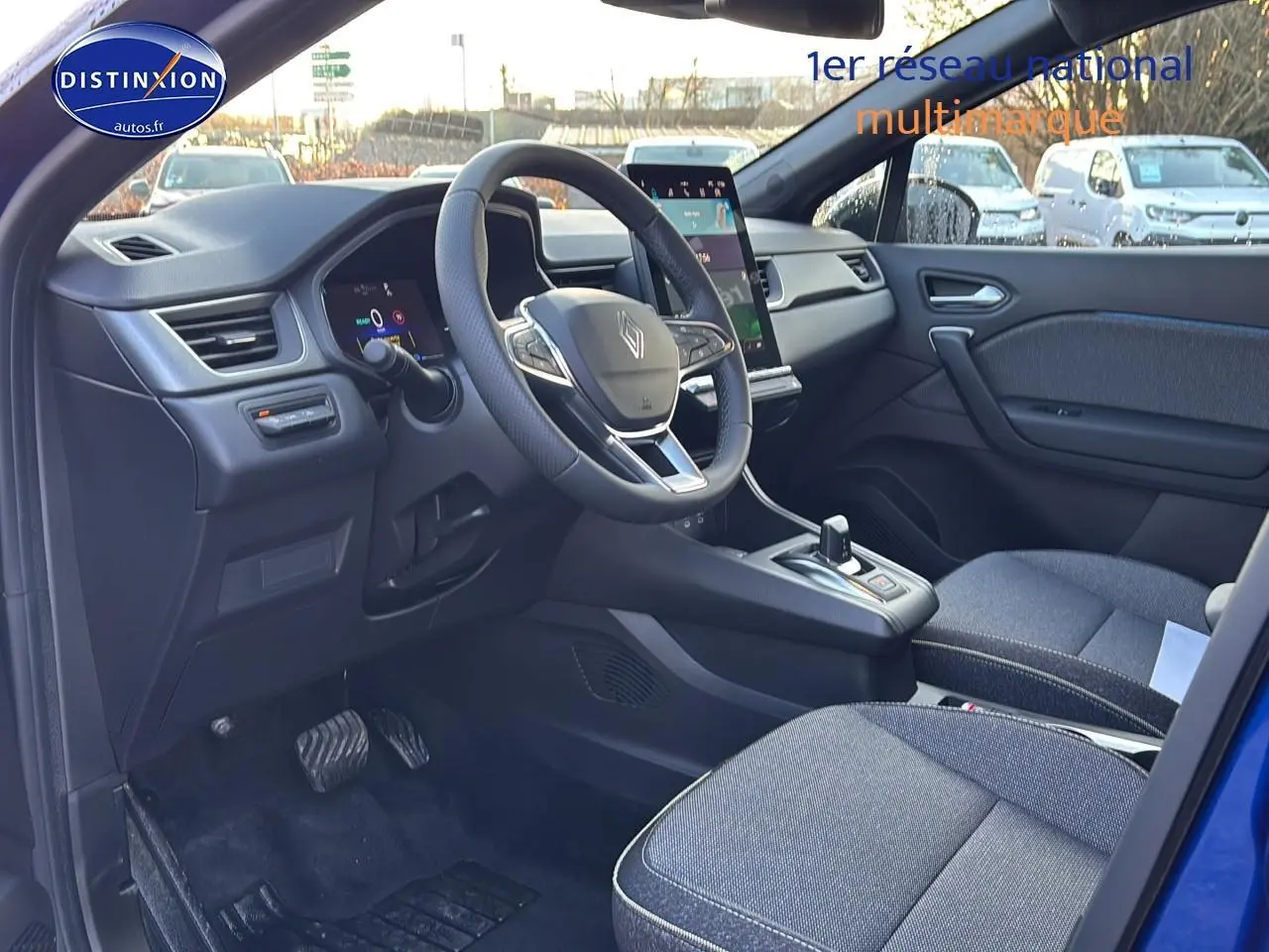 Intérieur avant droit du Renault Captur bleu iron, volant multifonction et écran tactile vertical visible.
