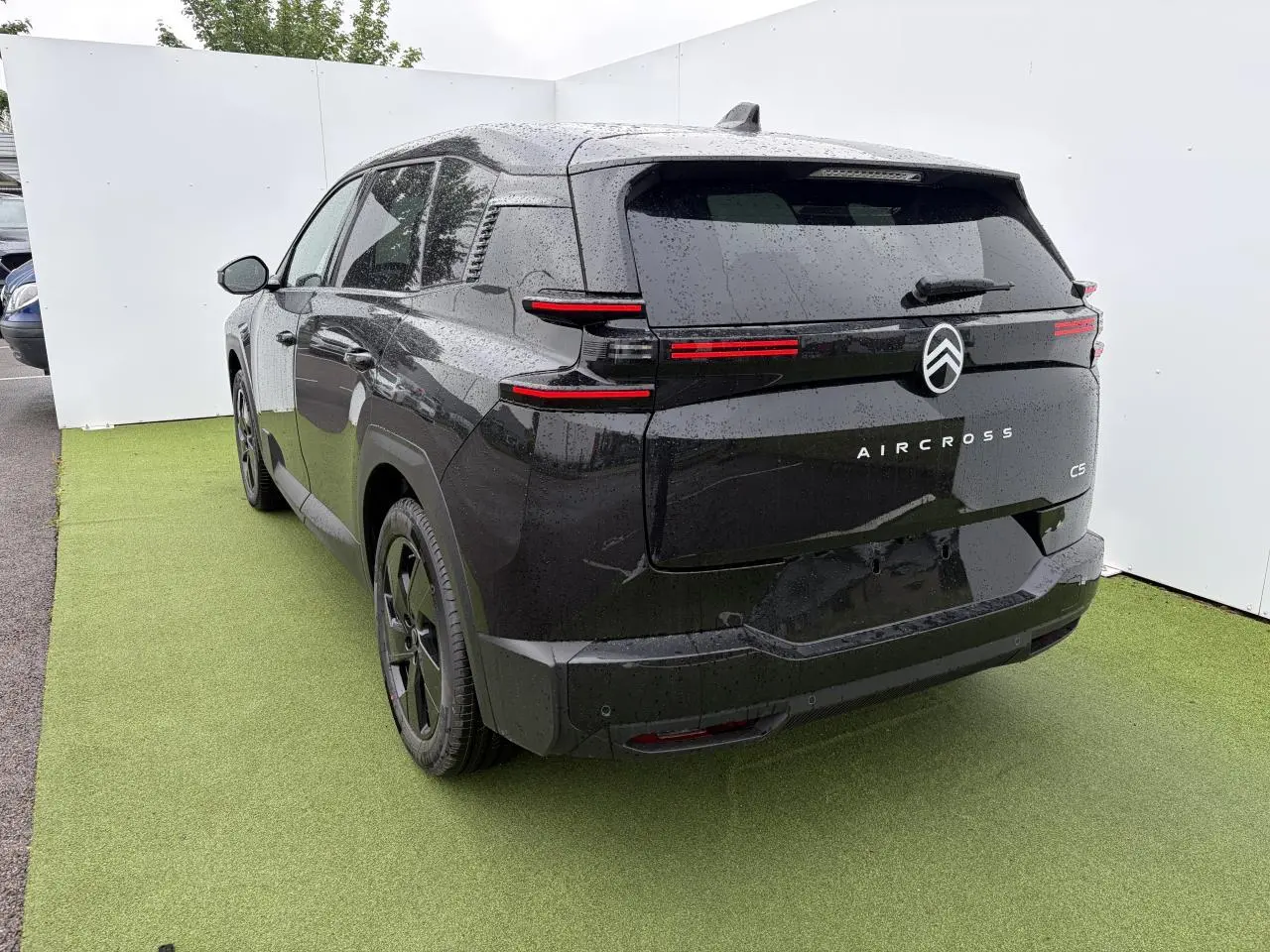 Vue 3/4 arrière droite du Citroën C5 Aircross noir métal avec feux arrière LED et toit panoramique visible.