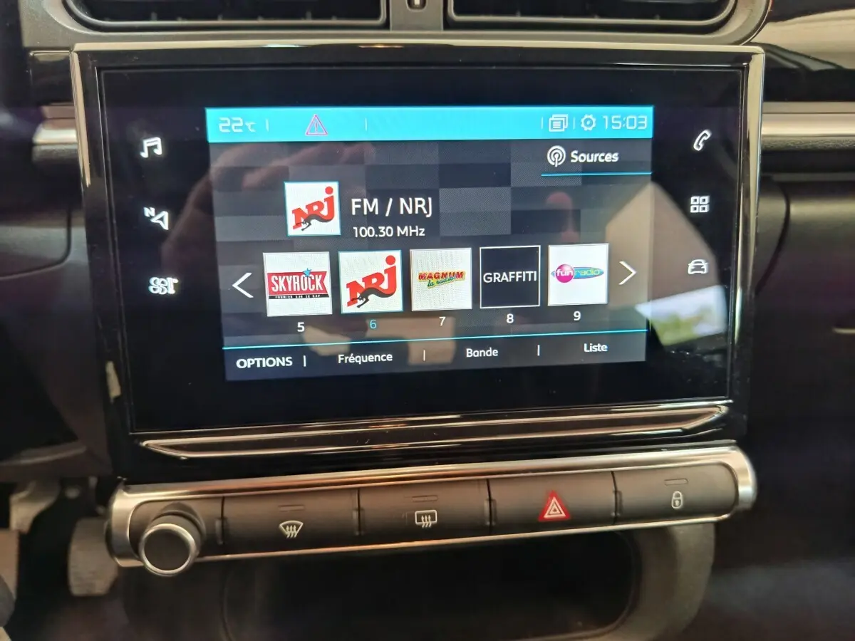 Écran tactile central de la Citroën C3 blanche, affichant les stations radio avec commandes en dessous.