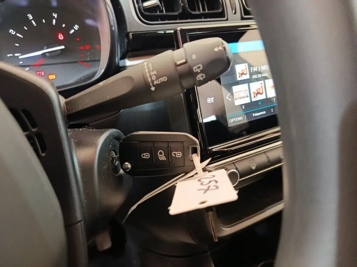 Gros plan intérieur côté conducteur sur le tableau de bord et la clé insérée d'une Citroën C3 blanche, écran tactile visible.