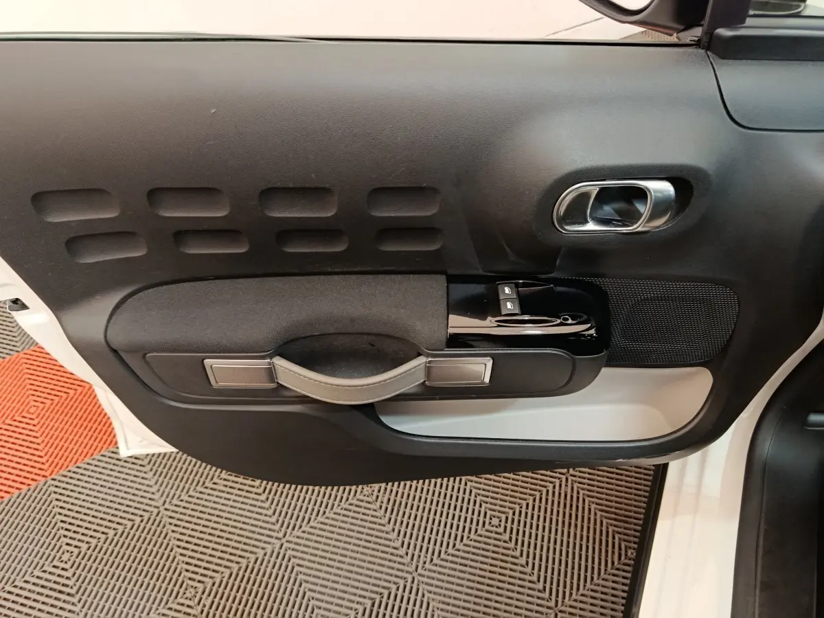 Vue rapprochée de la porte avant droite blanche d'une Citroën C3 2020 avec poignée noire et commandes de vitres.