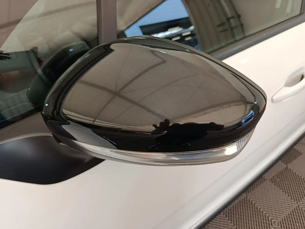 Rétroviseur extérieur droit noir brillant sur Citroën C3 blanche, vue rapprochée côté passager.