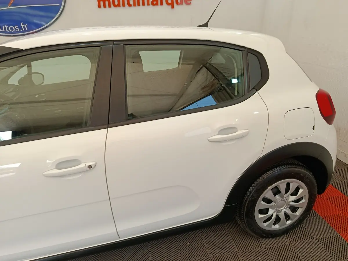 Vue latérale côté droit d'une Citroën C3 blanche de 2020, avec poignées de porte et jante acier visible.