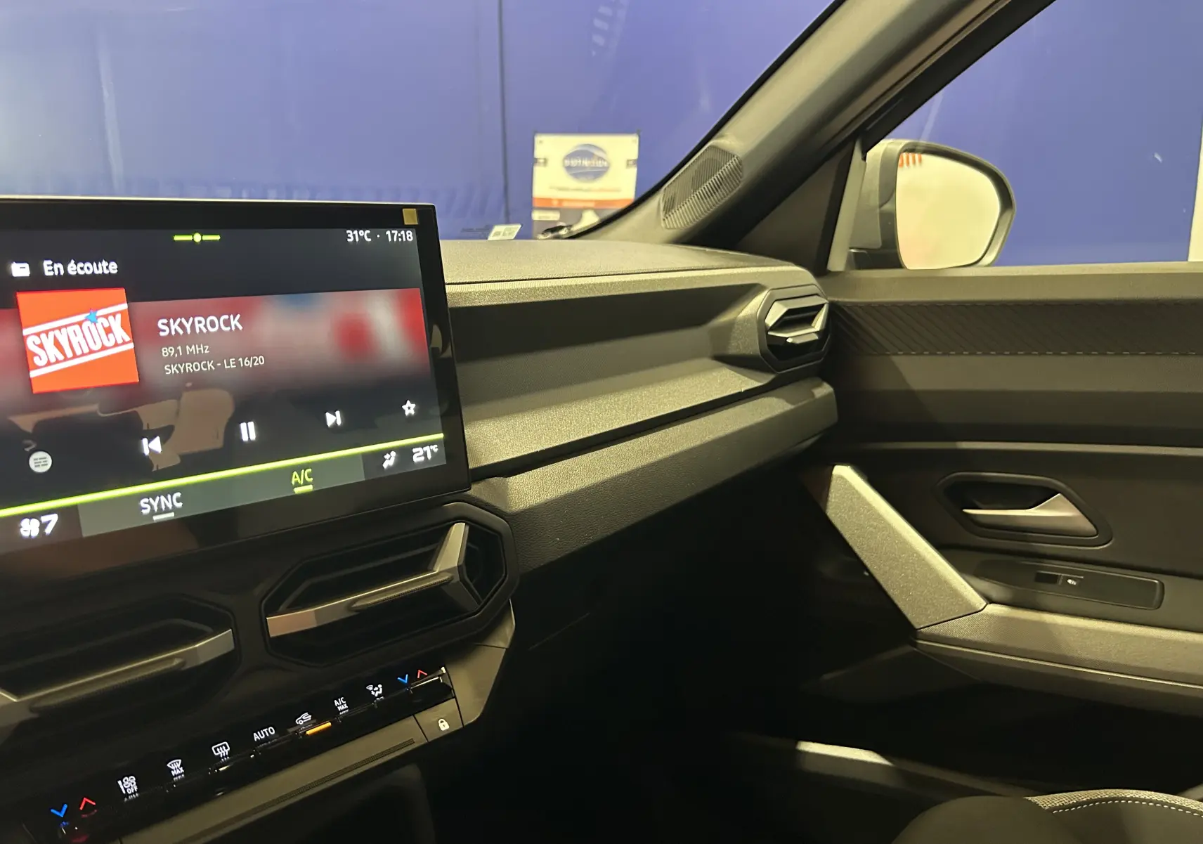 Intérieur du Dacia Bigster 2026 côté passager, avec tableau de bord moderne et écran tactile affichant la radio Skyrock.