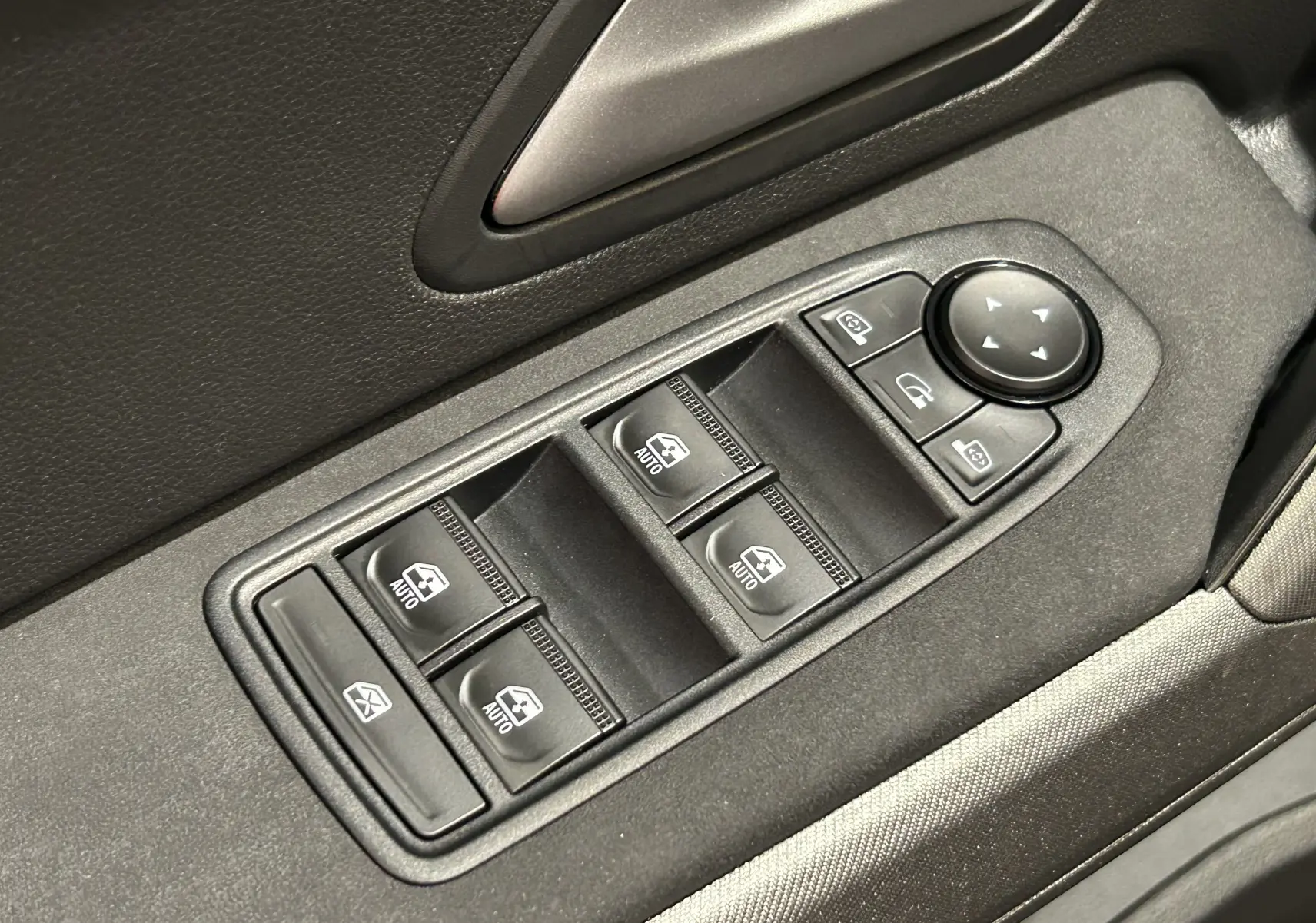 Gros plan sur les commandes de lève-vitres et réglage des rétroviseurs côté conducteur du Dacia Bigster 2026, intérieur noir.