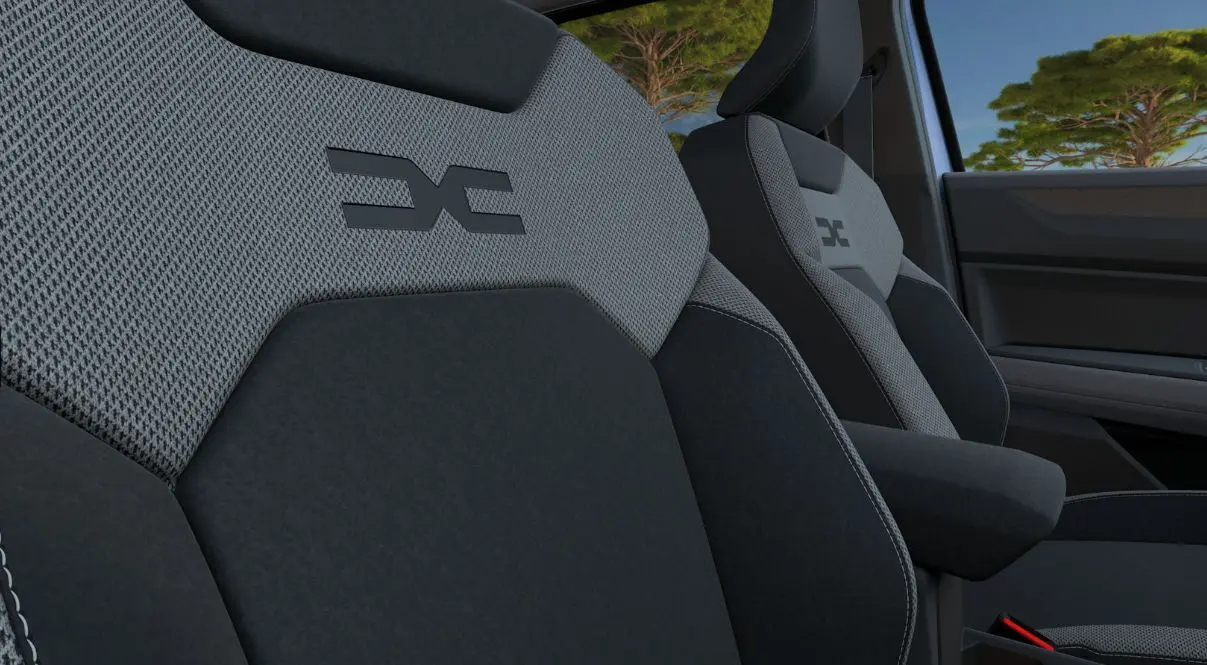 Gros plan sur les sièges avant gris et noirs du Dacia Bigster 2026 avec logo distinctif brodé sur l'appuie-tête.