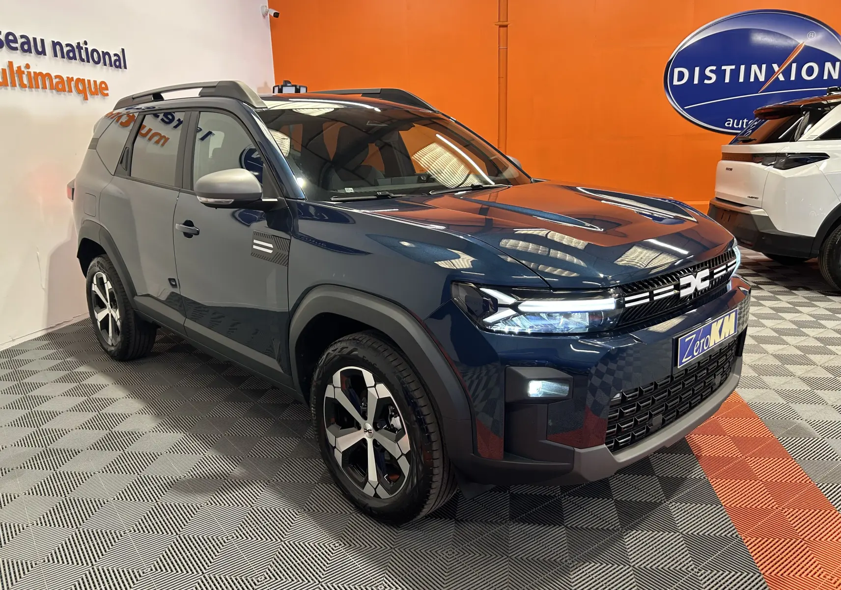 Dacia Bigster bleu indigo en 3/4 avant droit, avec calandre moderne et jantes bi-ton distinctives.