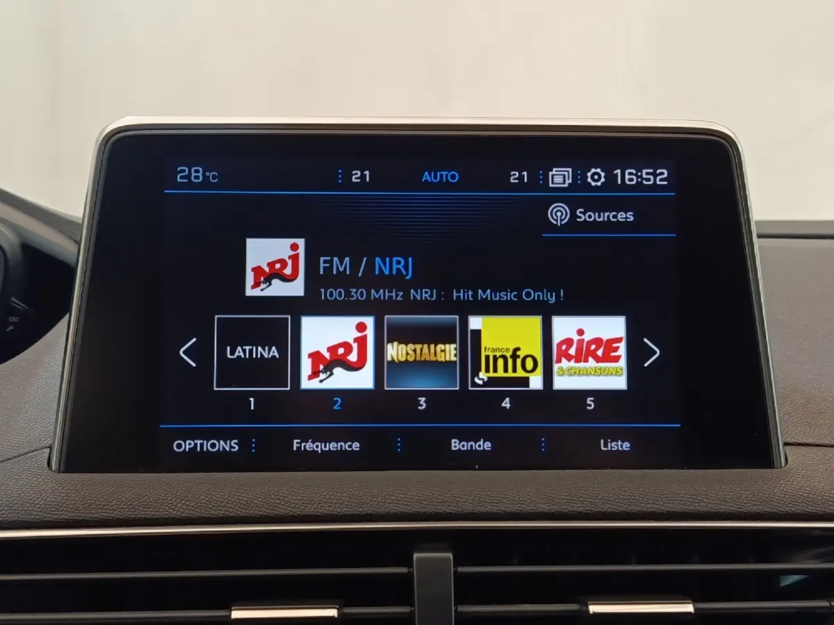 Écran tactile central du tableau de bord du Peugeot 5008 noir, affichant les stations radio FM avec interface moderne.