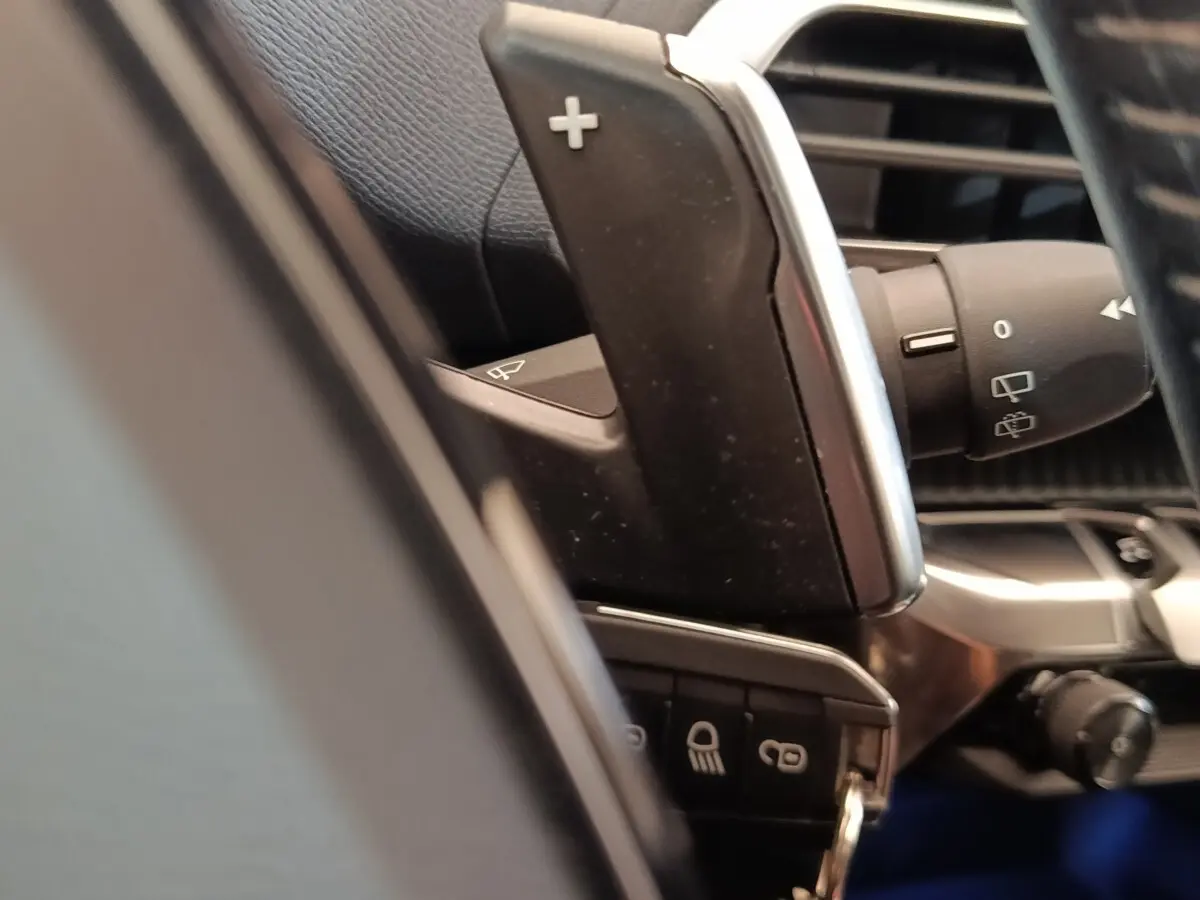 Gros plan sur la commande de palette de changement de vitesse au volant du Peugeot 5008 noir, intérieur cuir noir.