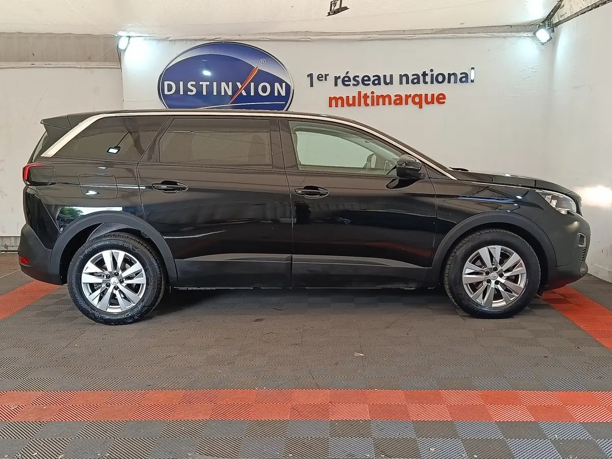 Profil côté gauche d'un Peugeot 5008 noir 2020, SUV avec vitres teintées et jantes alliage en intérieur showroom.