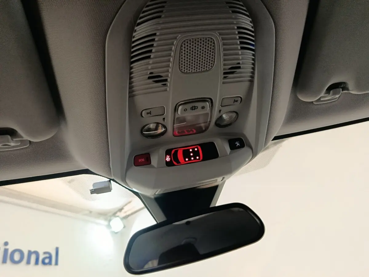 Vue intérieure en plongée du plafonnier et du rétroviseur central du Peugeot 5008 noir, avec commandes lumineuses activées.