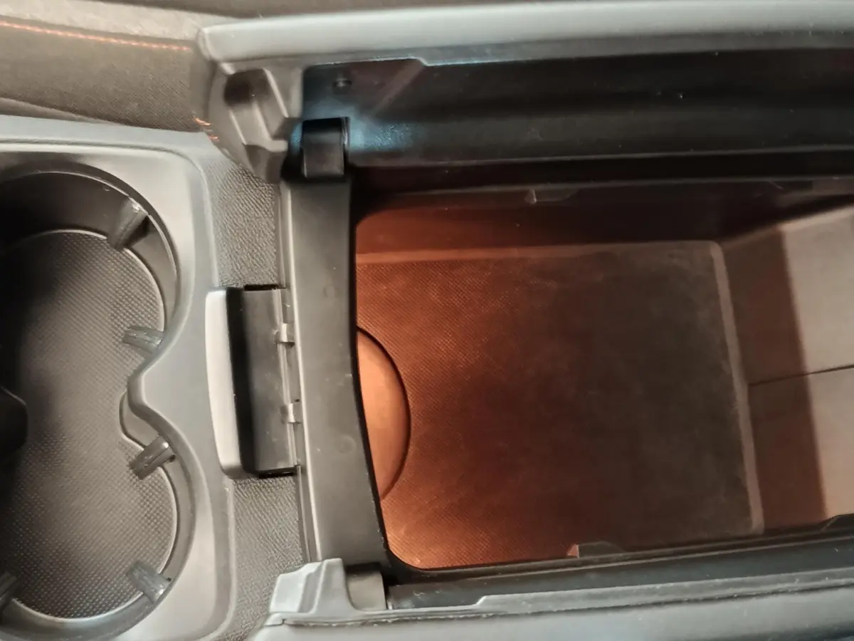 Vue rapprochée de la console centrale noire du Peugeot 5008, montrant un rangement intérieur ouvert et porte-gobelets.
