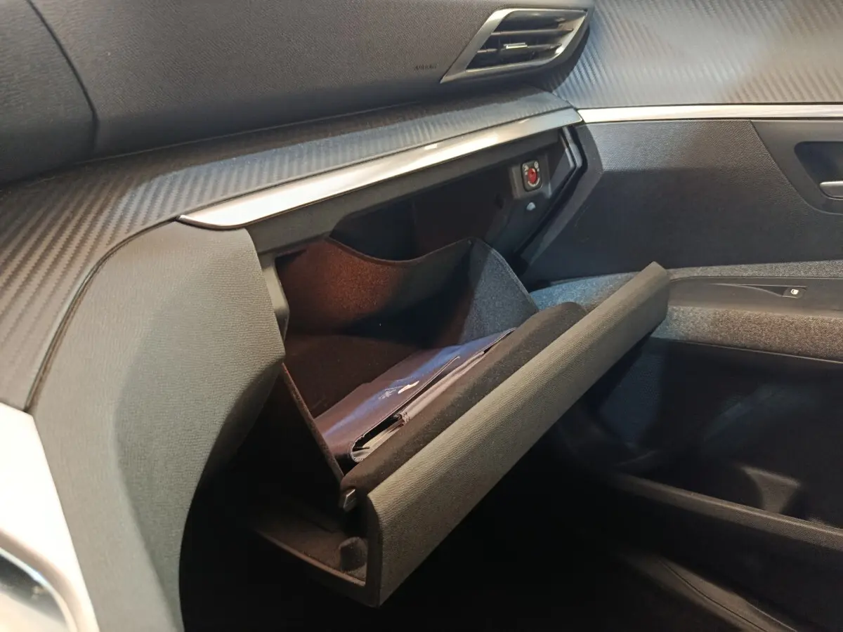 Vue intérieure côté passager du Peugeot 5008 2020 noir, boîte à gants ouverte avec livret visible.