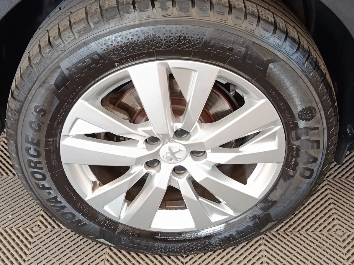 Gros plan sur la roue avant droite du Peugeot 5008 noir, mettant en valeur la jante alliage argentée et le pneu.