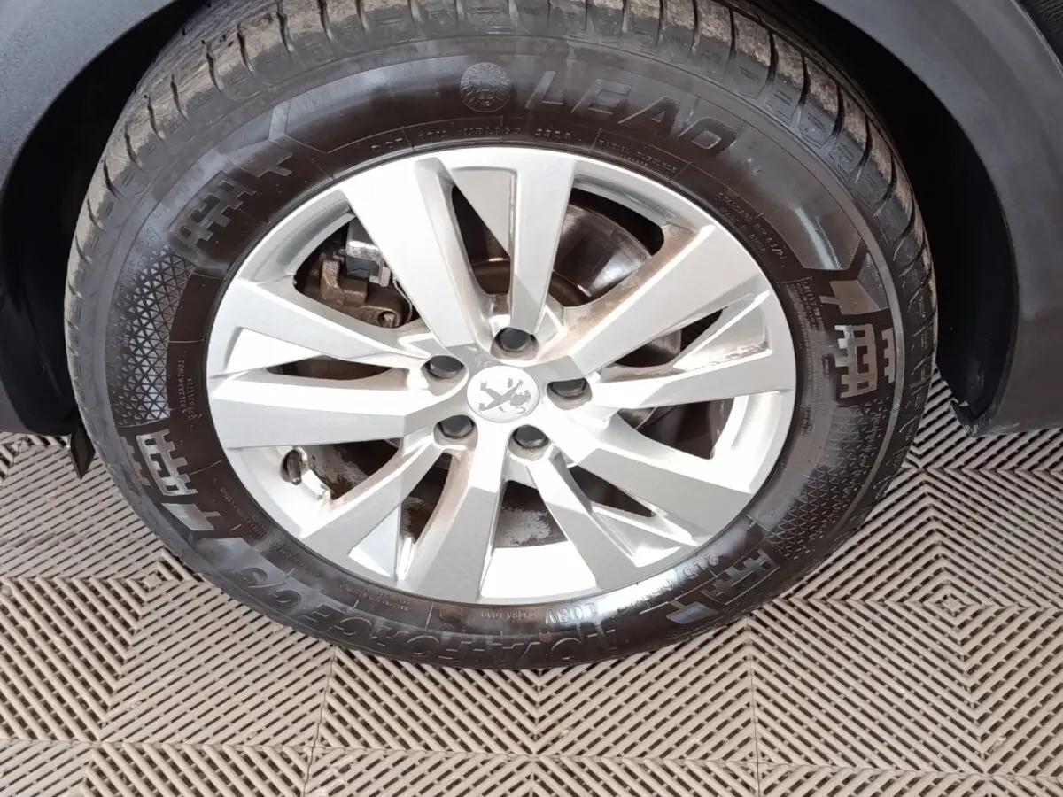 Gros plan sur la jante argentée et le pneu noir d'un Peugeot 5008 2020, avec logo lion au centre.