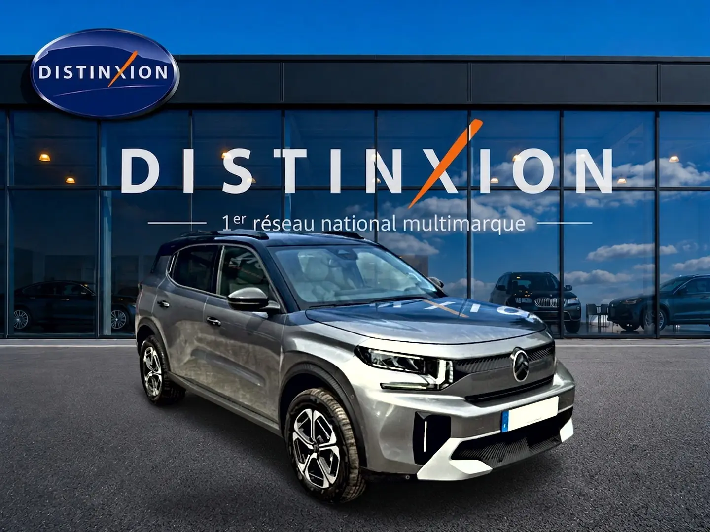 Citroën C3 Aircross gris mercury vue 3/4 avant droit devant un bâtiment Distinxion avec jantes alu noires et argentées.
