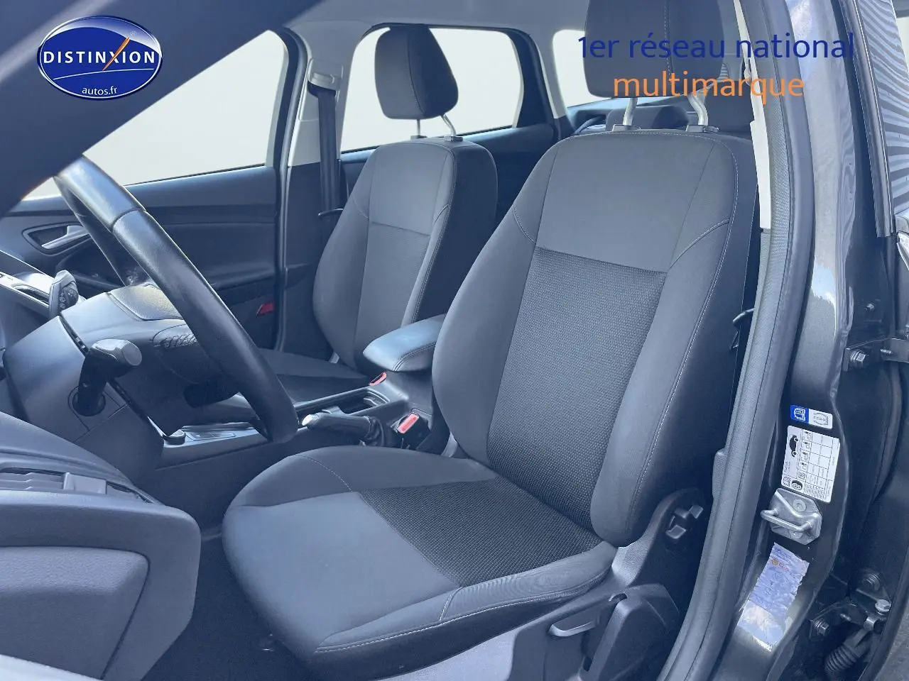 Vue intérieure côté conducteur de la Ford Focus SW 2018 avec sièges tissu noir et portière ouverte gris magnetic metal.