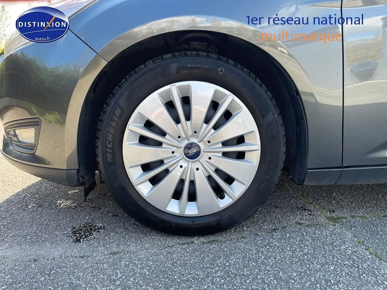 Gros plan sur la roue avant gauche d'une Ford Focus SW gris magnetic metal, mettant en valeur la jante et le logo Ford.