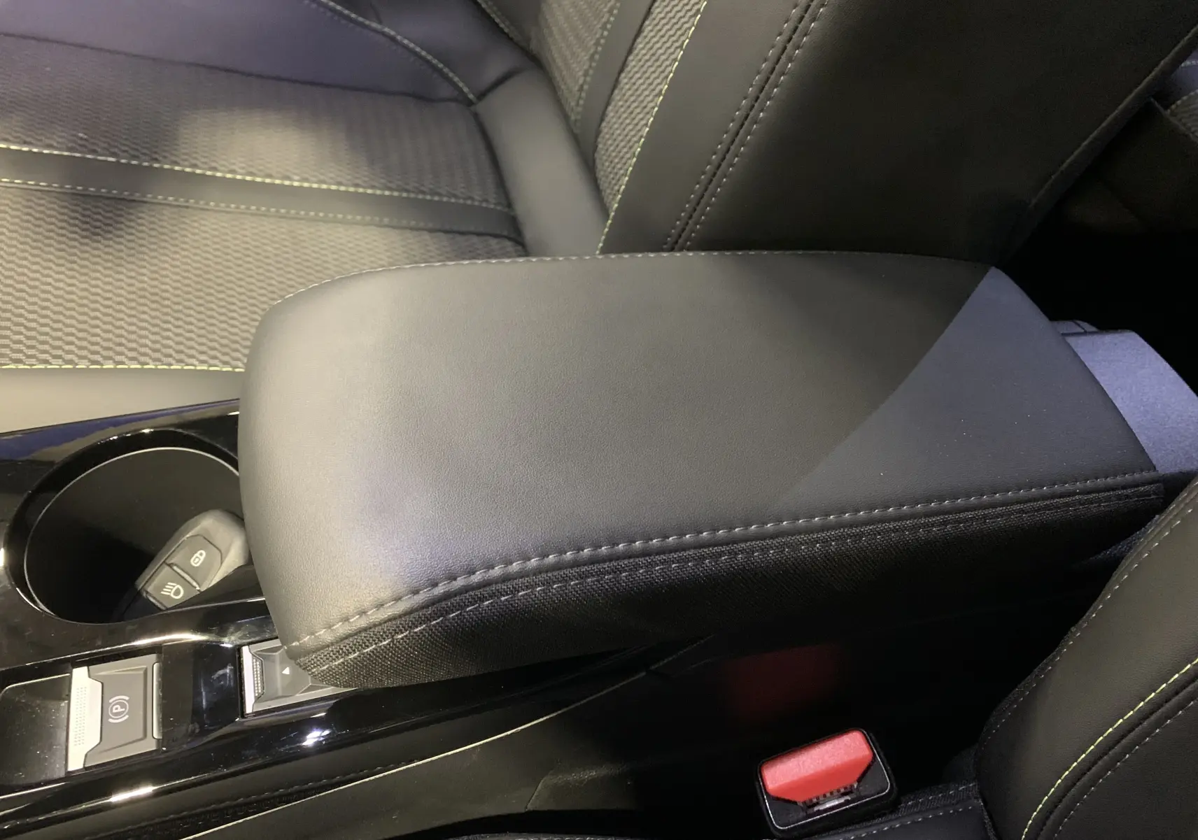 Accoudoir central en cuir noir avec surpiqûres vertes dans l'habitacle du Peugeot 2008 BlueHDi 130 GT 2023.