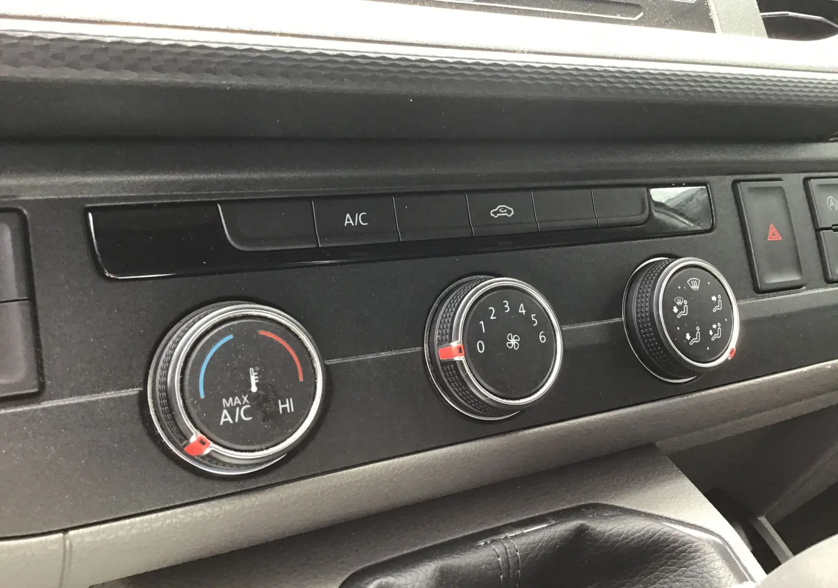 Gros plan sur les commandes de climatisation du Volkswagen Transporter 6.1 blanc, avec boutons rotatifs et affichage clair.