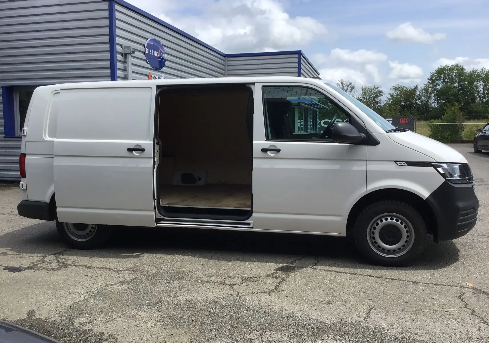 Vue latérale droite d'un Volkswagen Transporter 6.1 blanc avec porte coulissante ouverte montrant l'espace de chargement vide.
