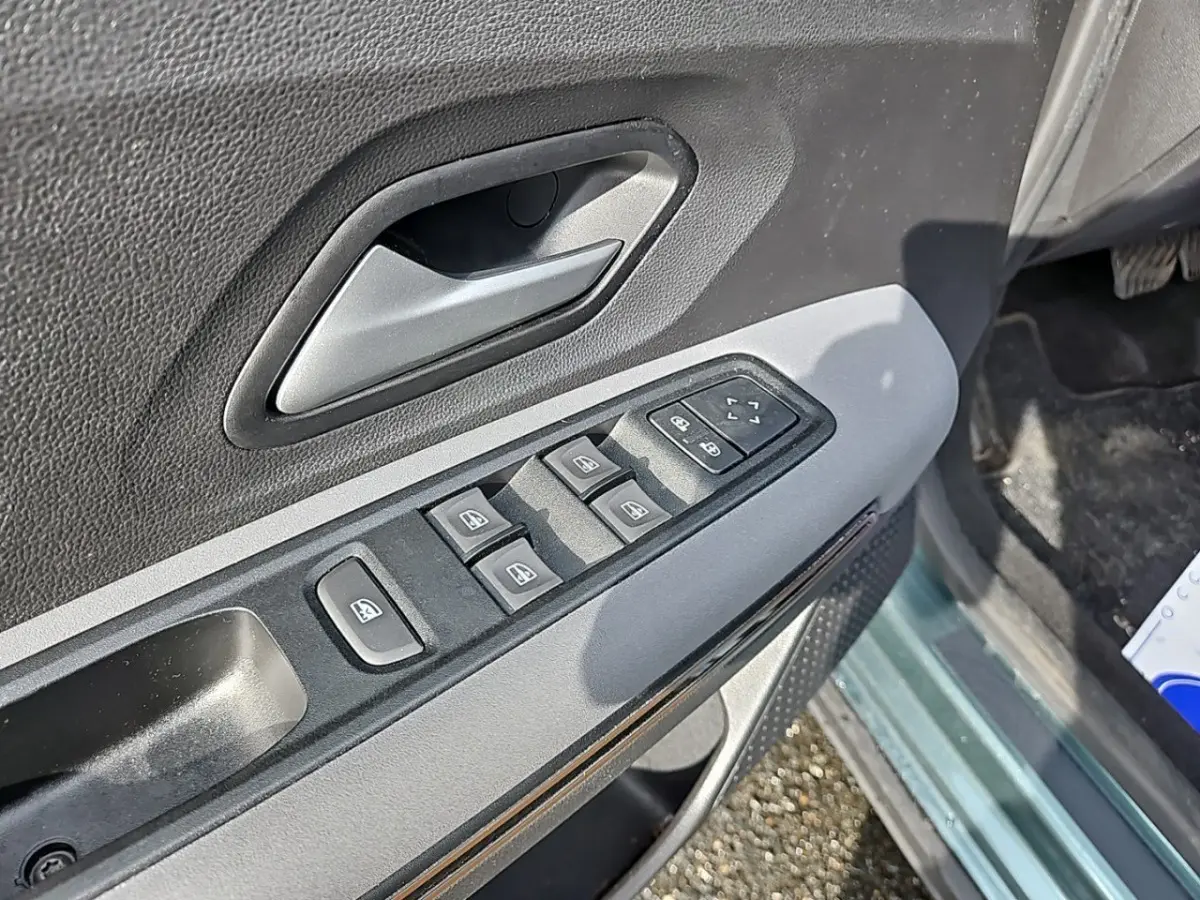Gros plan sur la commande des vitres électriques côté conducteur d'une Dacia Jogger vert 2024, intérieur noir et gris.
