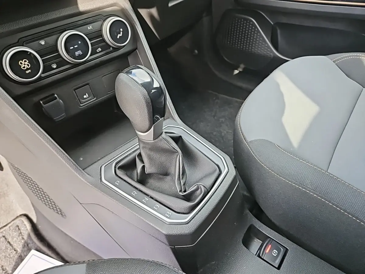 Le levier de boîte automatique noir du Dacia Jogger Extreme Hybrid vu de dessus, avec console et sièges gris.