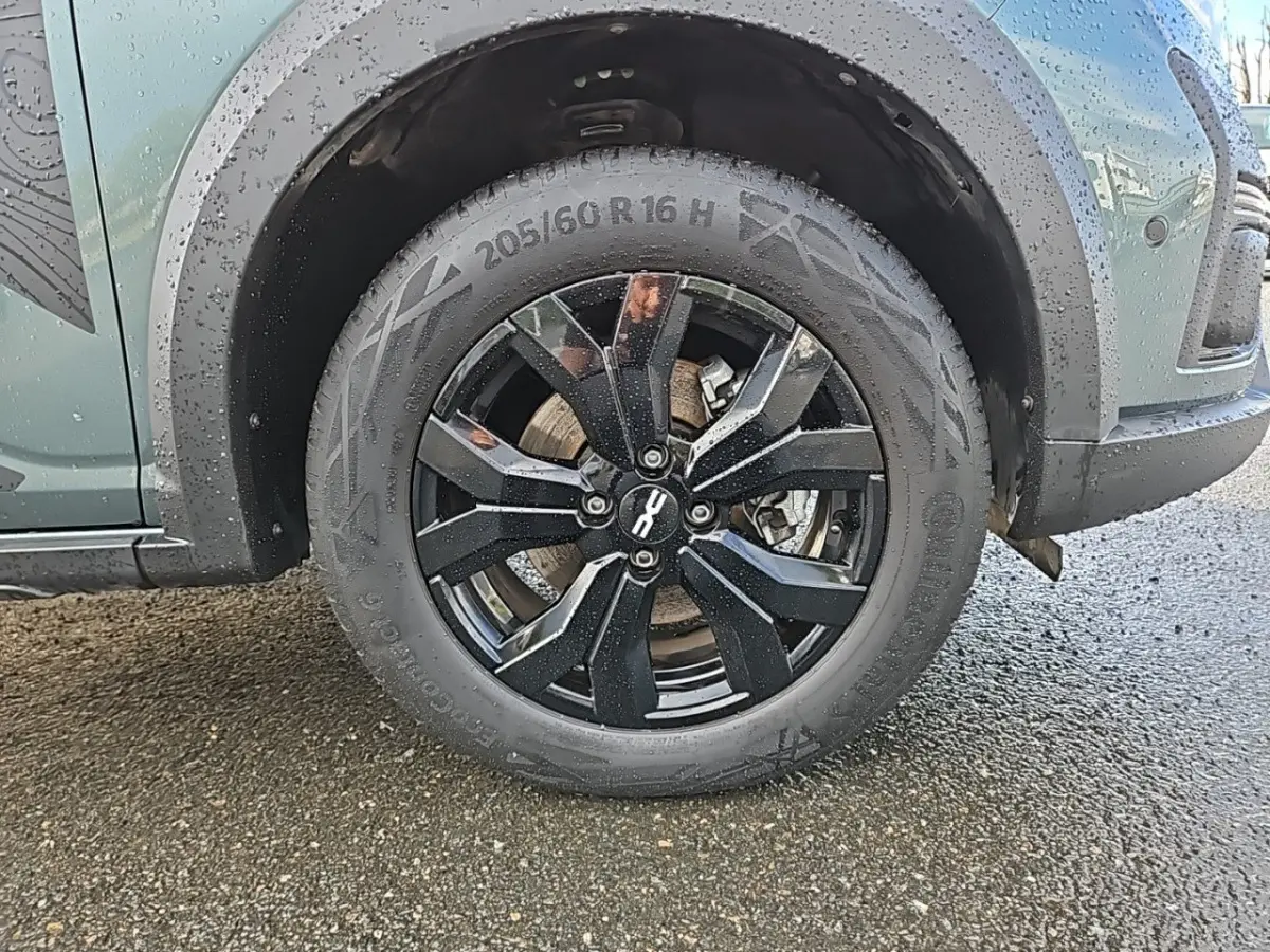 Gros plan sur la roue avant gauche noire du Dacia Jogger vert 2024 avec jante au design moderne.