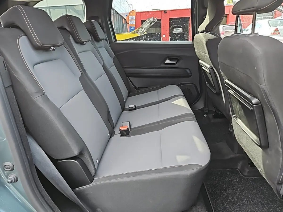 Vue latérale intérieure sur la banquette arrière grise et noire du Dacia Jogger Extreme Hybrid vert 2024.
