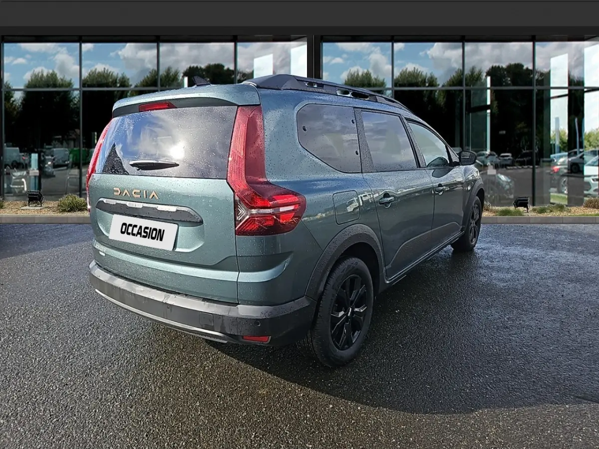 Vue 3/4 arrière droite du Dacia Jogger vert avec feux arrière en forme de L et barres de toit noires.