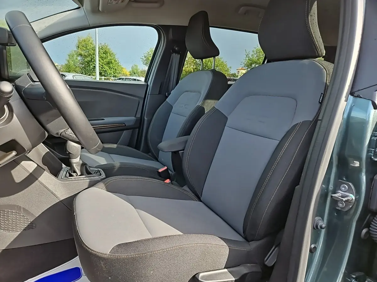 Vue intérieure côté gauche montrant les sièges avant gris et noirs du Dacia Jogger Extreme Hybrid 2024 vert.
