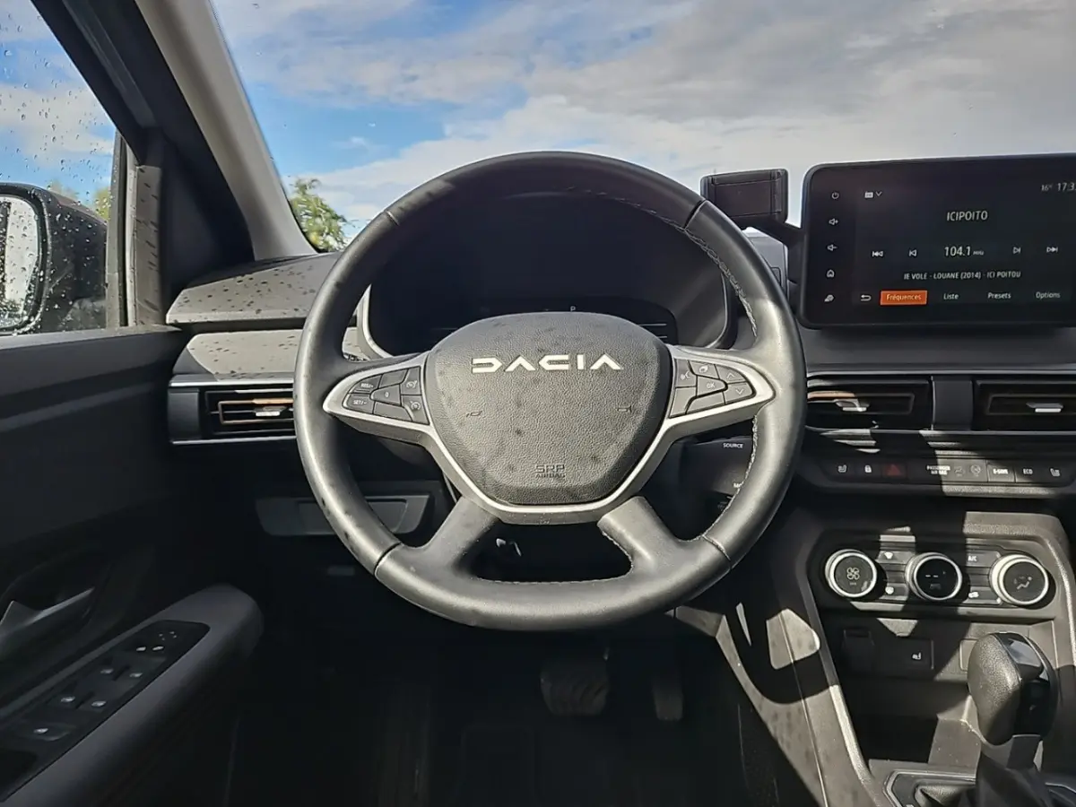 Vue frontale du volant noir DACIA Jogger 2024 avec tableau de bord et écran tactile central allumé.