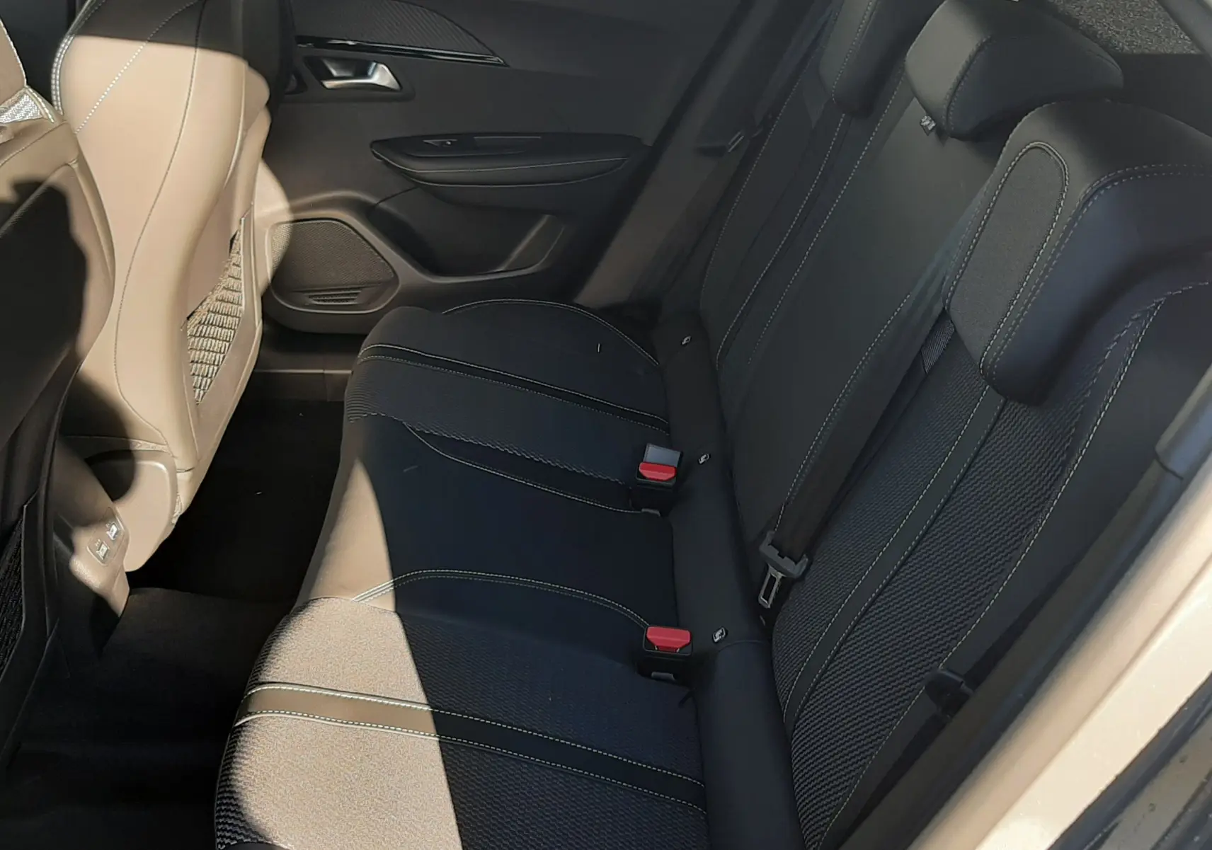 Vue intérieure côté droit des sièges arrière noirs avec surpiqûres claires du Peugeot 2008 gris sélénium 2025 hybride.